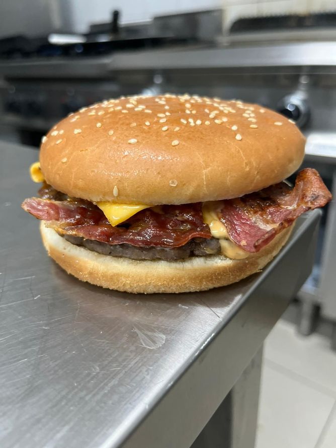 Cheeseburger ai semi di sesamo con pancetta su un bancone in acciaio inox