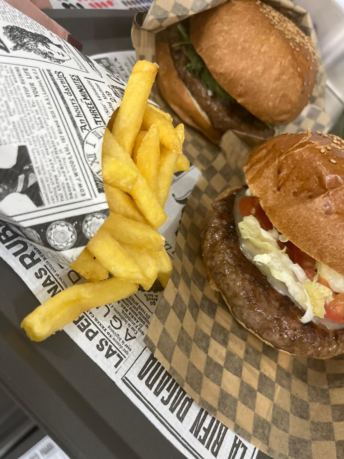 Due hamburger e patatine fritte su carta a quadretti in un vassoio da fast food.
