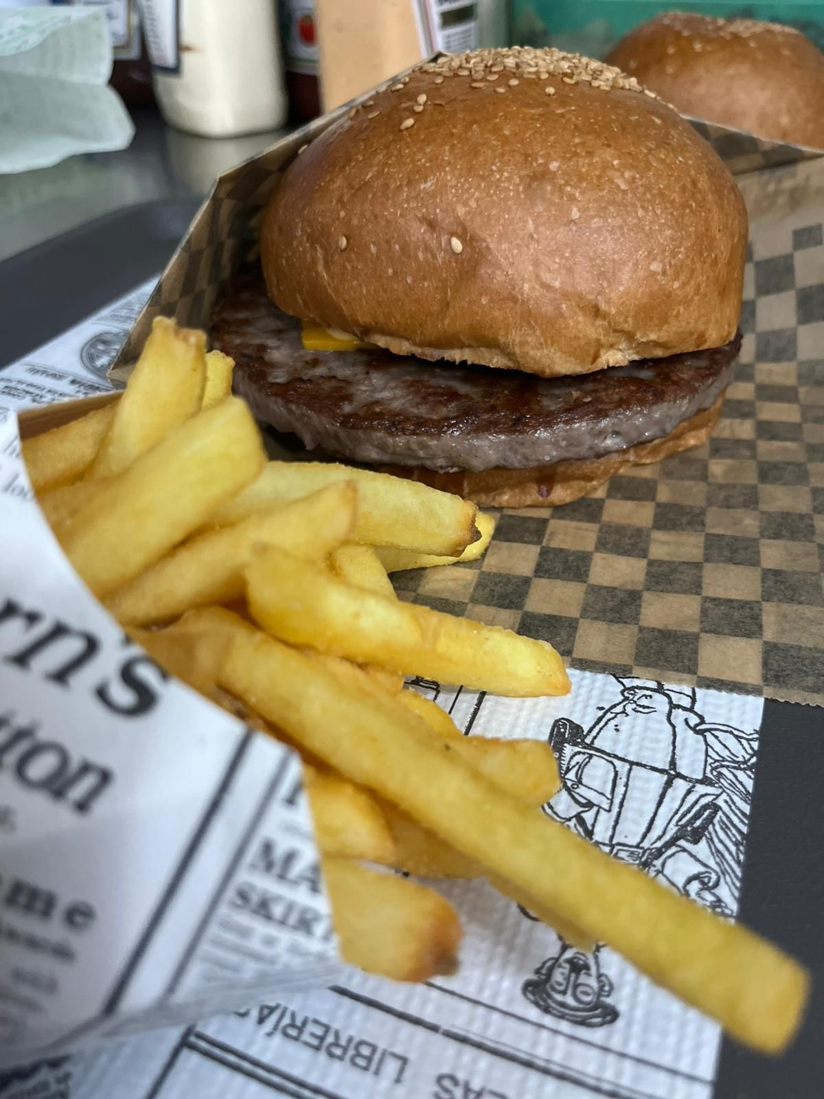 Hamburger e patatine fritte su un tavolo di ristorante servito su carta a quadretti.