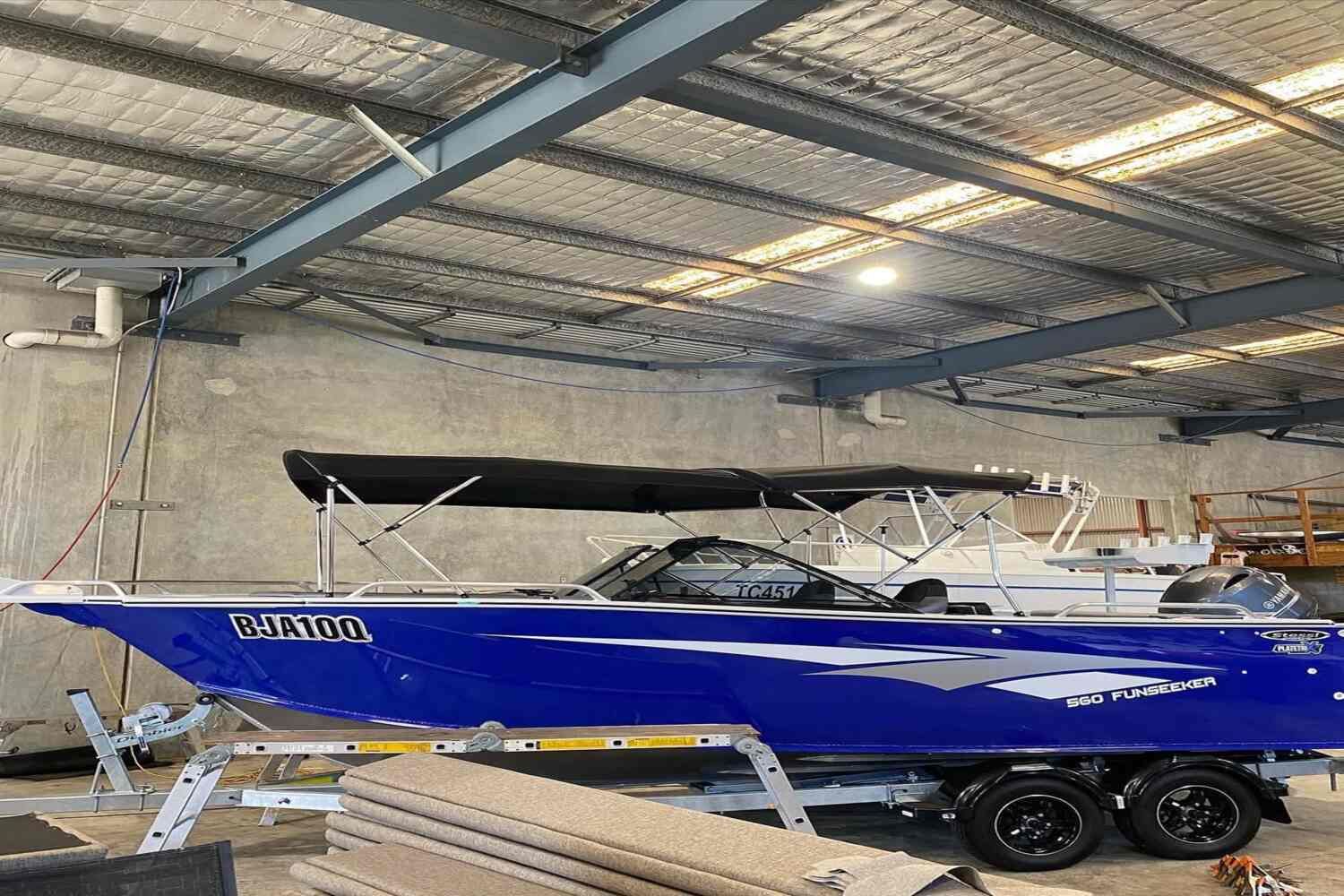 A Blue Boat Is Sitting On A Trailer In A Warehouse — Currumbin Trimmers In Currumbin Waters, QLD