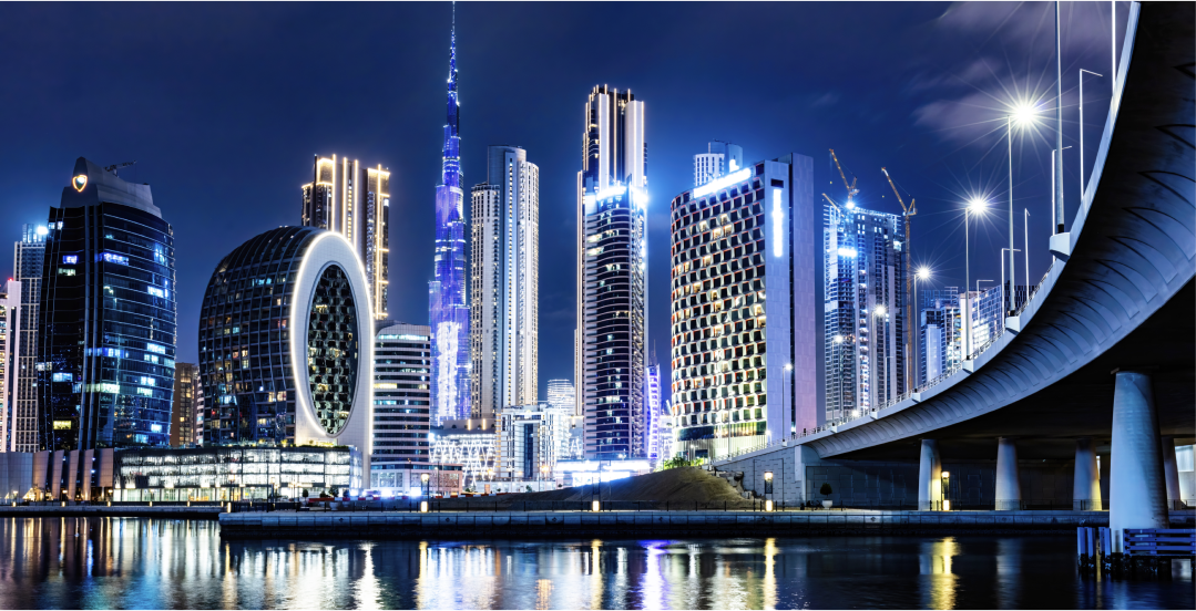 A city skyline at night with a bridge in the foreground.