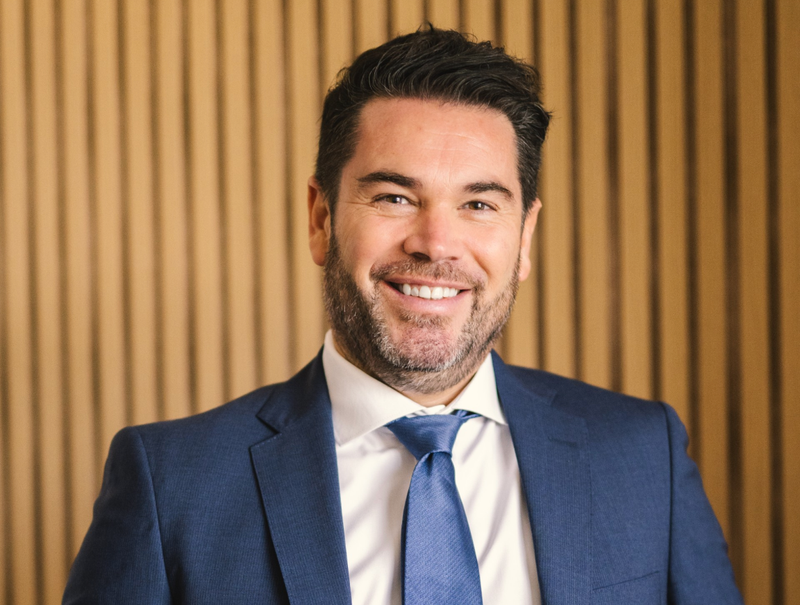 A man in a suit and tie is smiling for the camera.