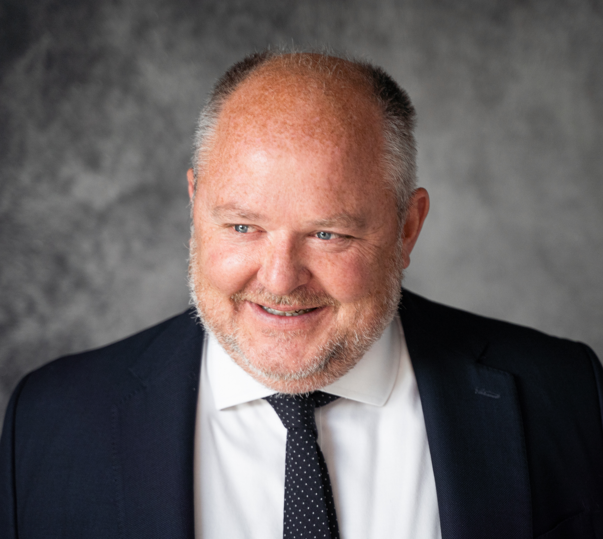 A man in a suit and tie is smiling for the camera.