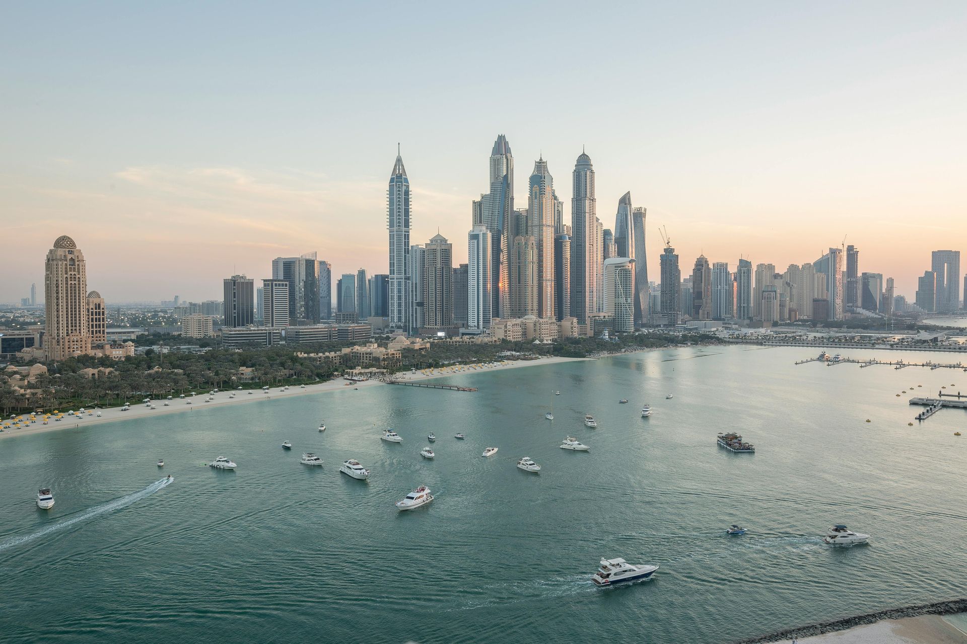 Dubai Marina skyline at sunset with boats on calm water