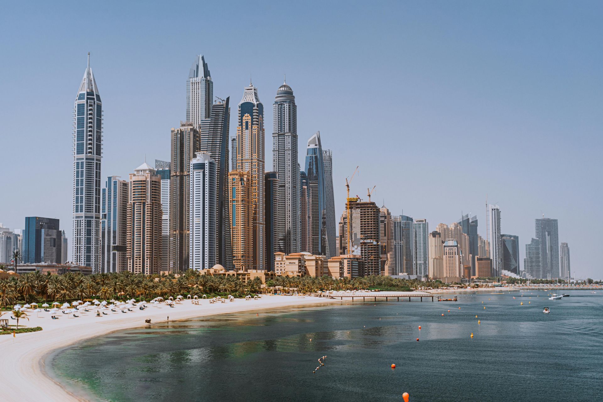 A city skyline with a beach in the foreground and a body of water in the background.