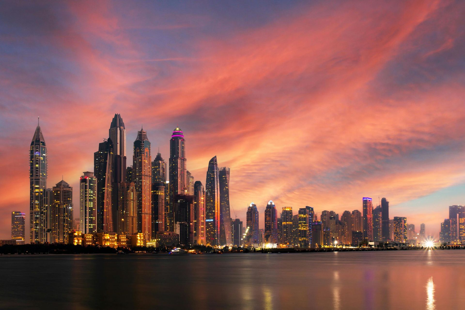 A city skyline overlooking a body of water at sunset.