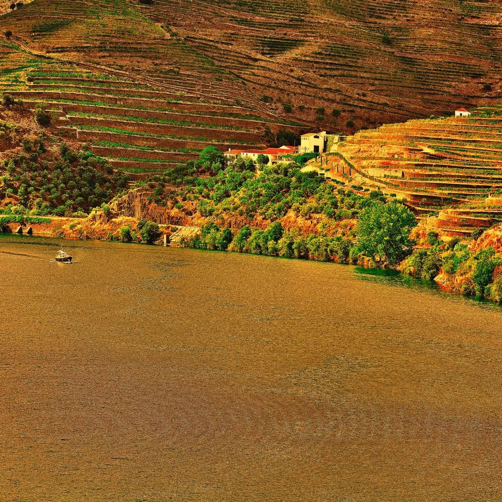 Terraced hillside village beside a river, with autumn-colored trees and earthy farmland.
