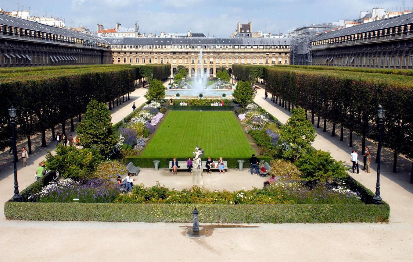 Formal French garden with central fountain, trimmed hedges, and symmetrical pathways flanked by rows of trees