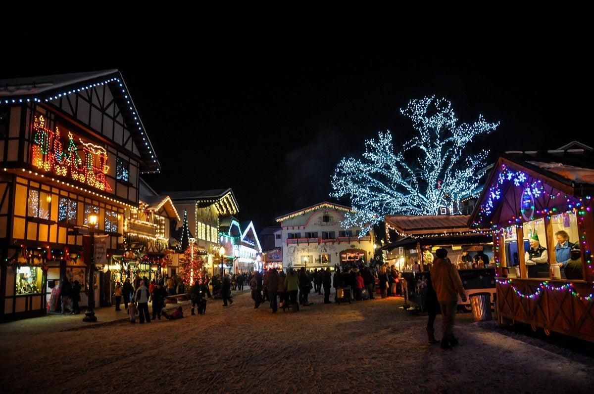 Holiday market at night with glowing lights, decorated stalls, and crowds in a festive square