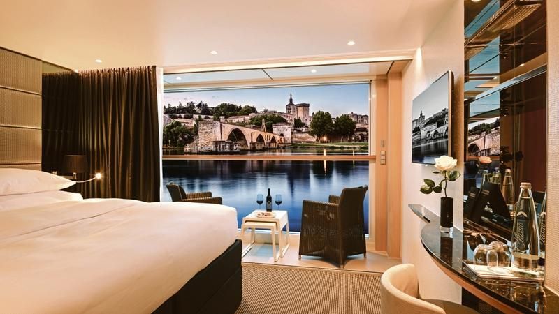 Luxury hotel room with king bed, lake view, and city skyline at sunset