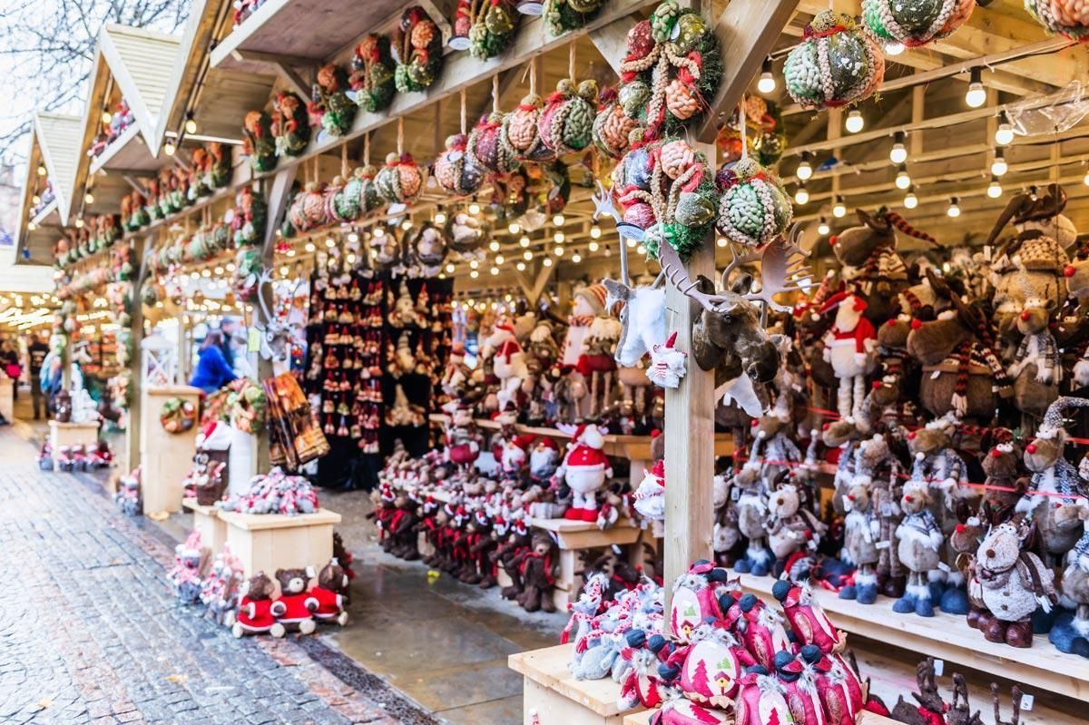 Christmas market stall filled with colorful holiday ornaments, stuffed toys, and festive decorations at night