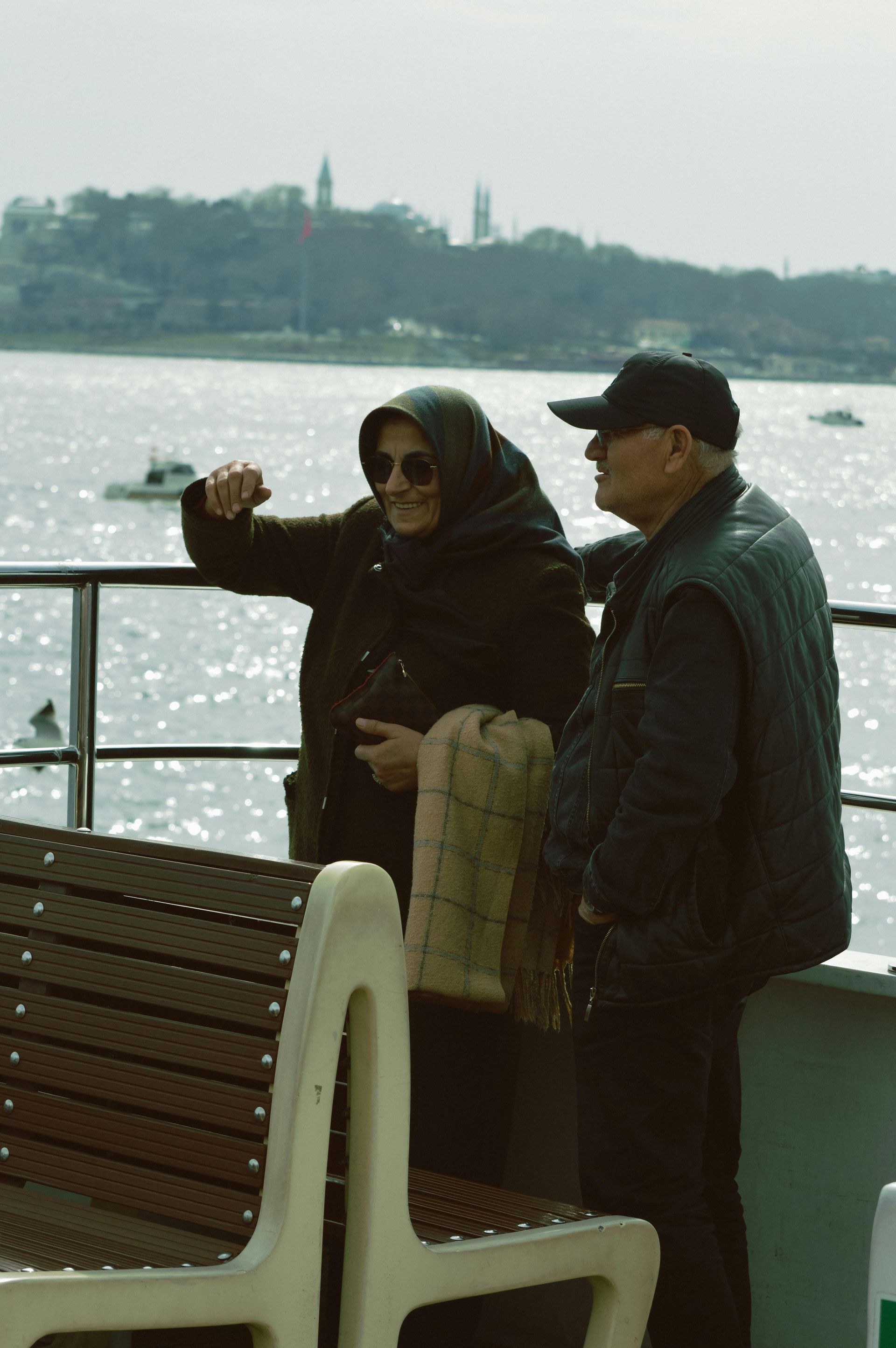 A man and a woman are standing on a boat looking at the water.