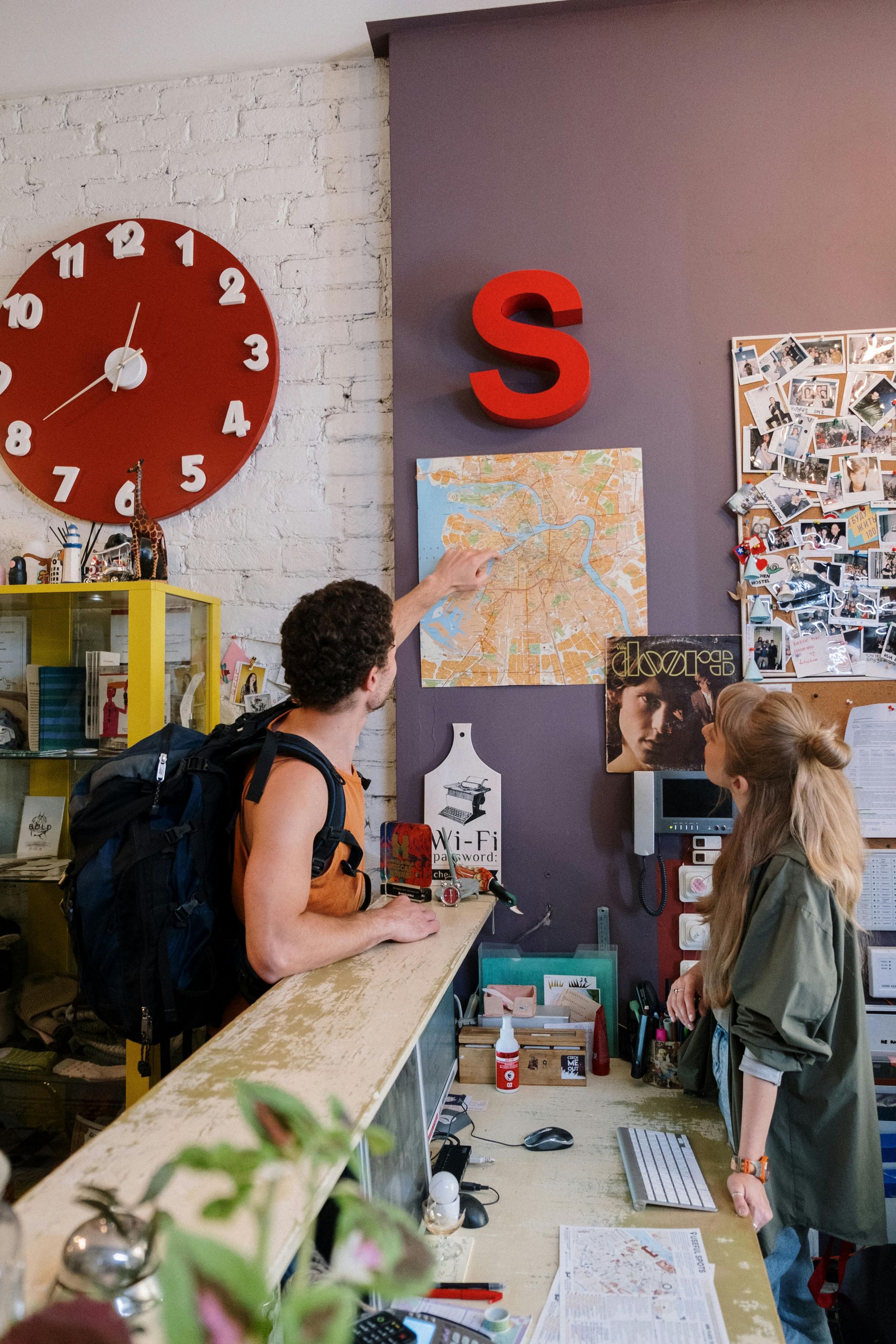 A man and a woman are standing at a counter pointing at a map.