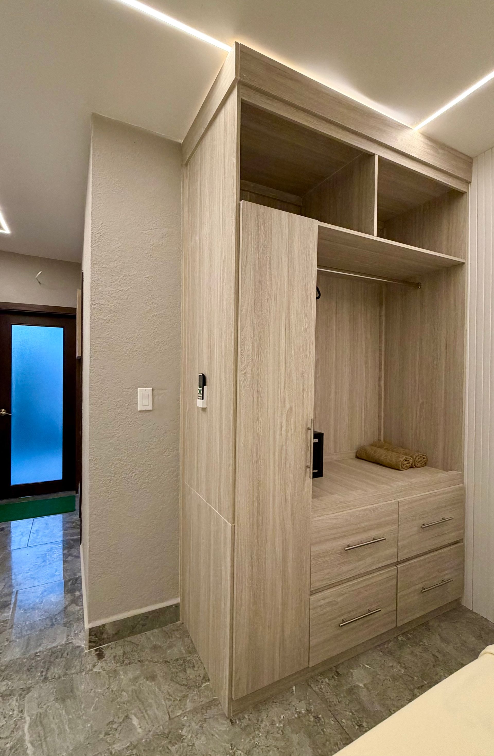 Built-in wooden wardrobe with drawers and hanging space in a tiled room