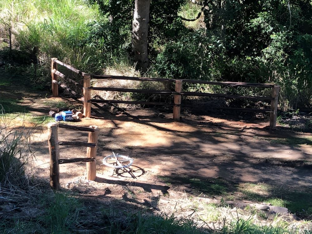 A Bicycle Is Parked In Front Of A Wooden Fence In The Woods — D.T. Fencing In Bakers Creek, QLD