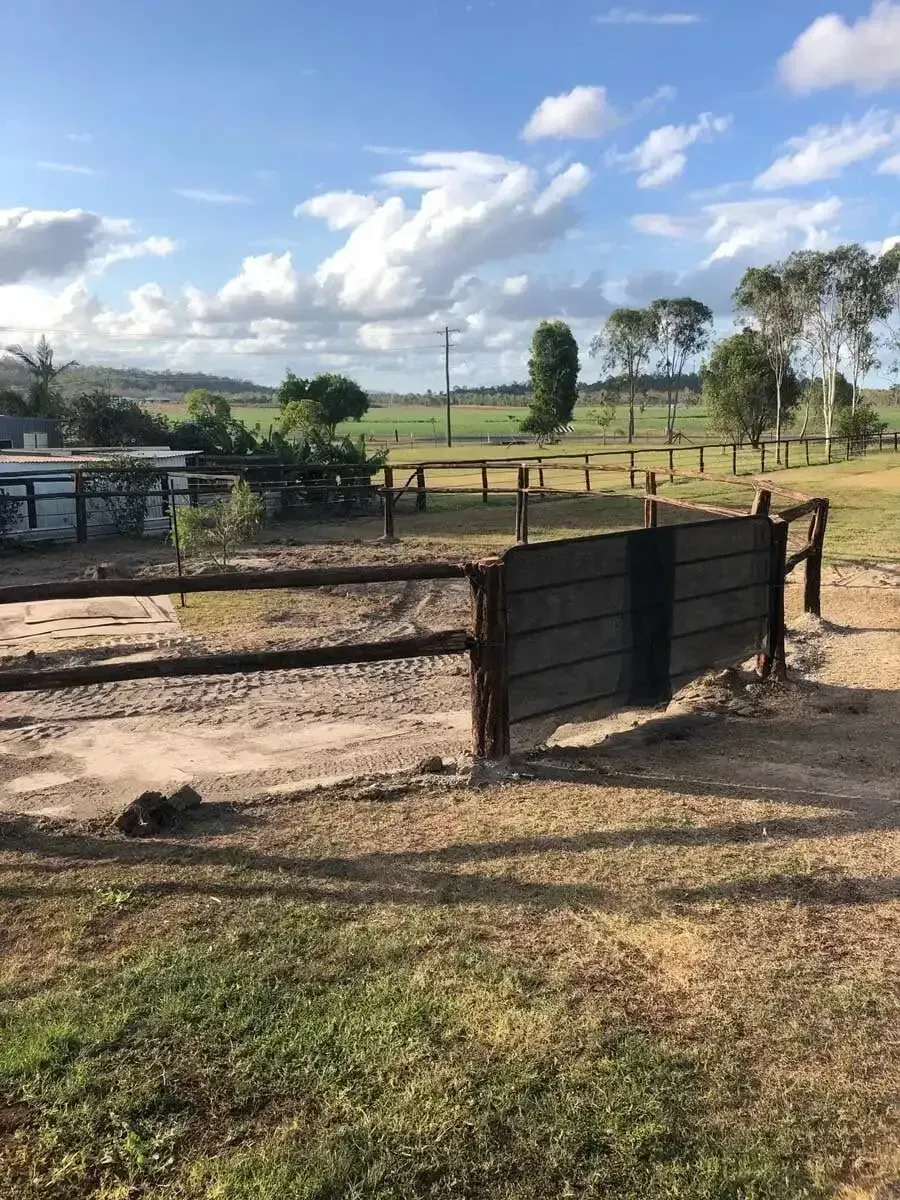 A wooden fence surrounds a dirt field with trees in the background. — D.T. Fencing In Bakers Creek, QLD