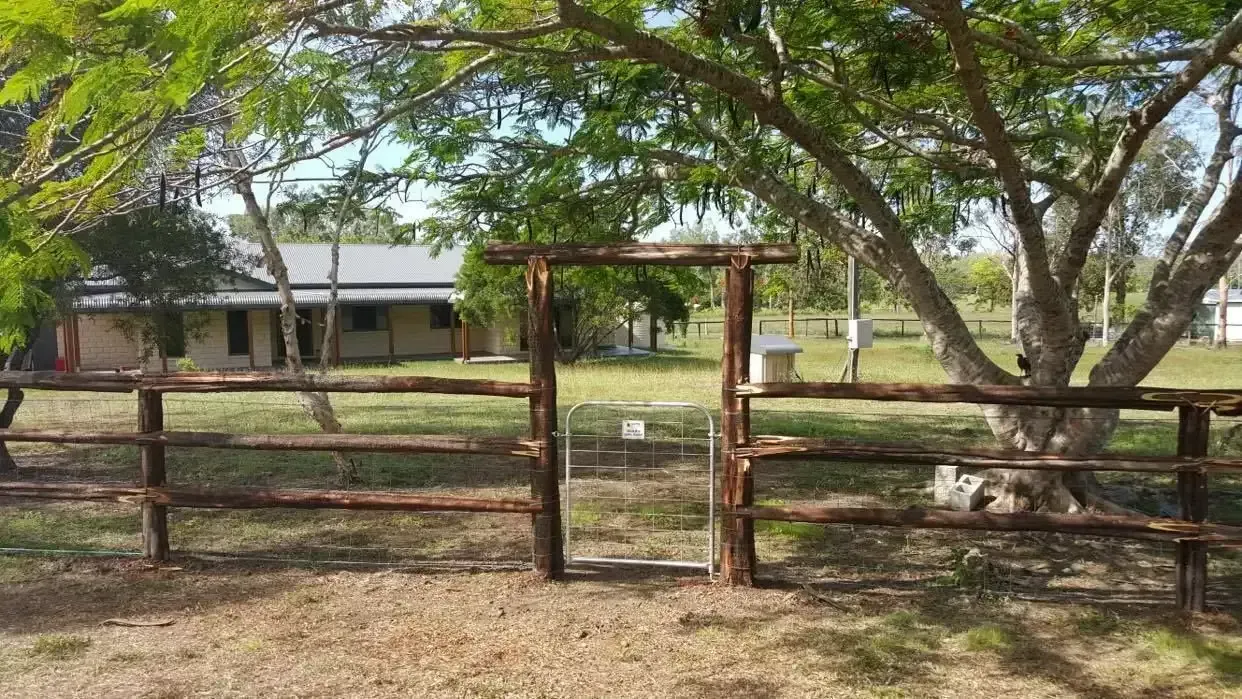 A wooden fence with a gate in front of a house. — D.T. Fencing In Bakers Creek, QLD
