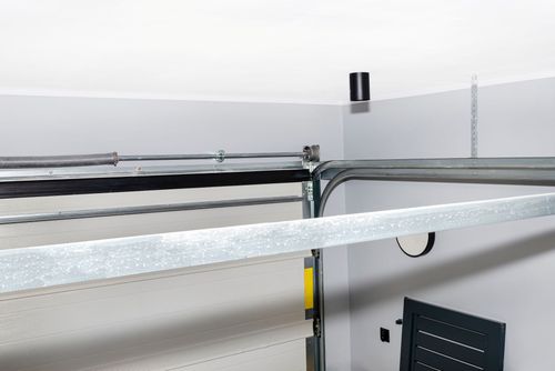Metal shelving and cables in a white utility room, with a black device mounted on the wall.