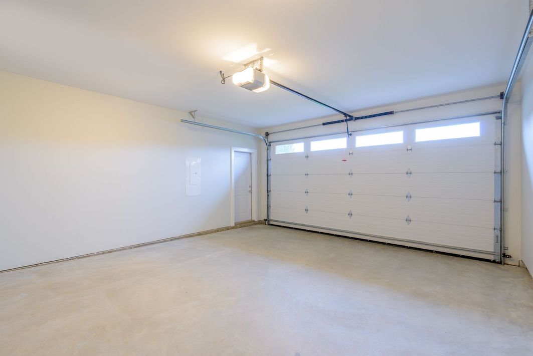 Empty white garage interior with closed double garage door and ceiling lights