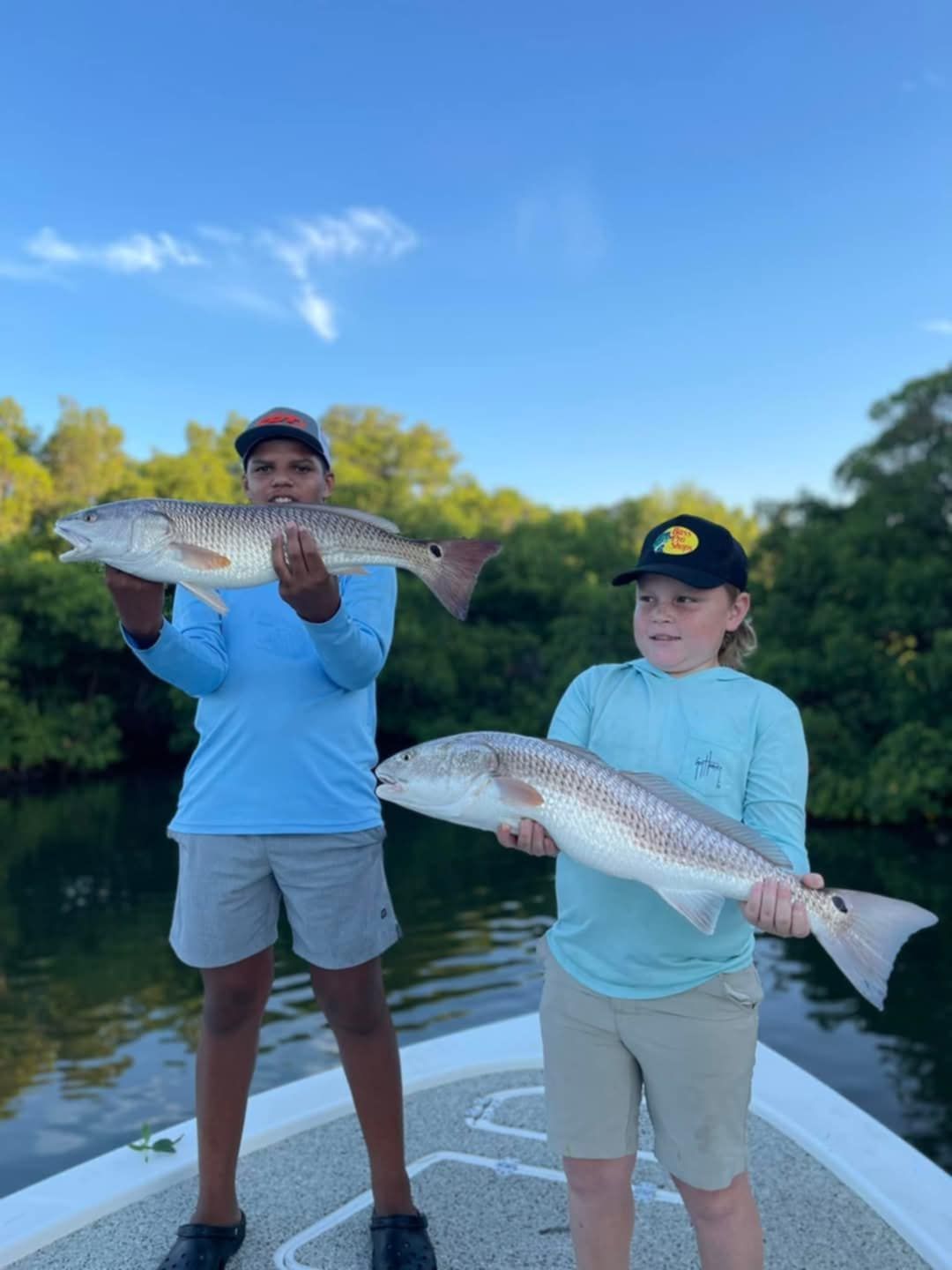 Two boys holding up fish they caught