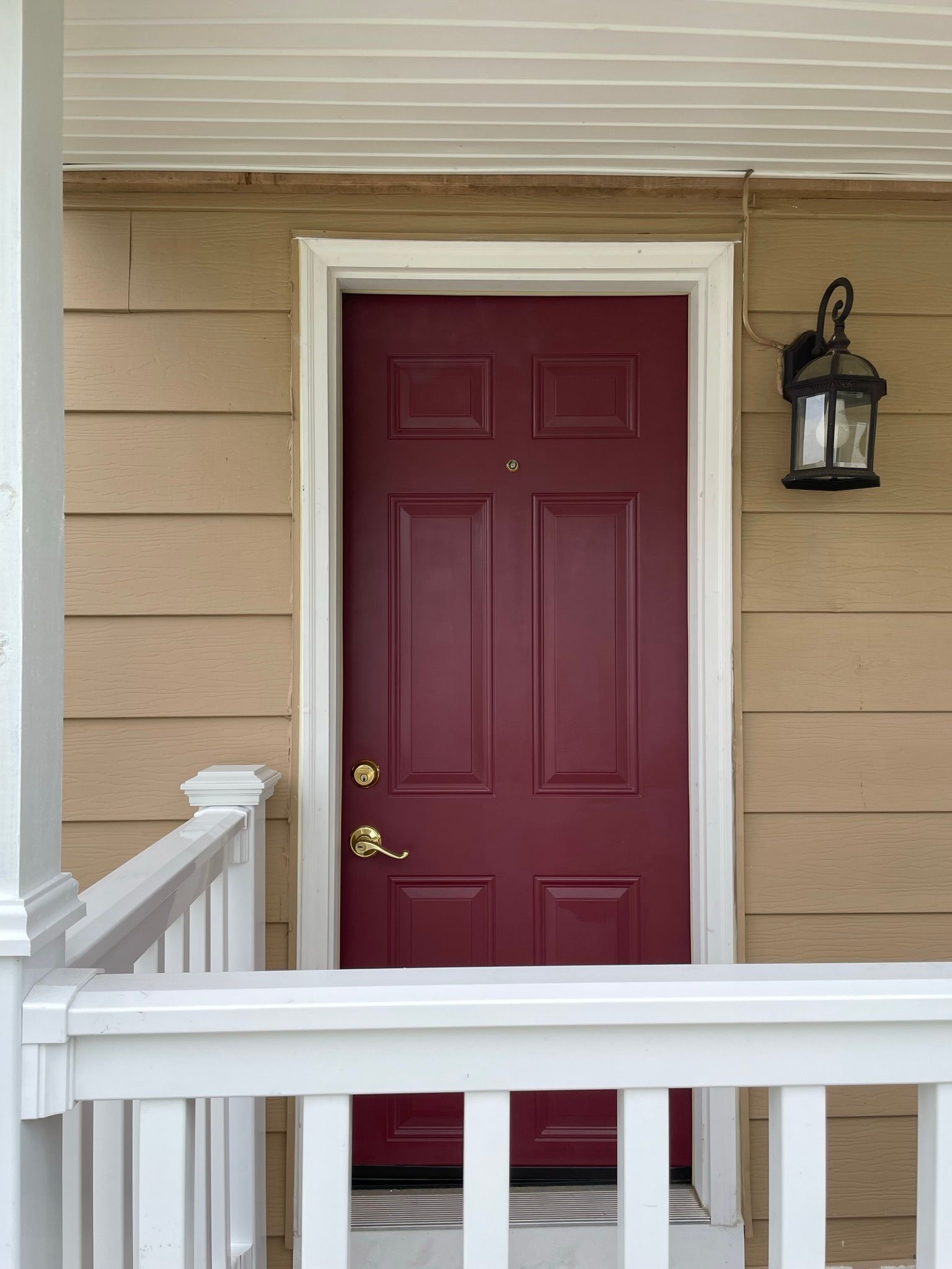 A red door on a house with a white railing