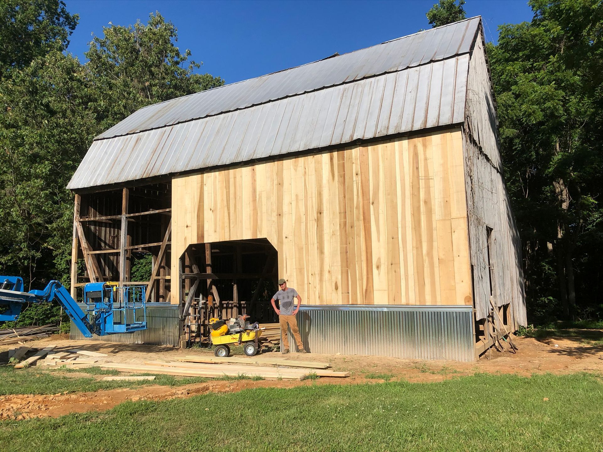 A man is standing in front of a barn that is being remodeled.