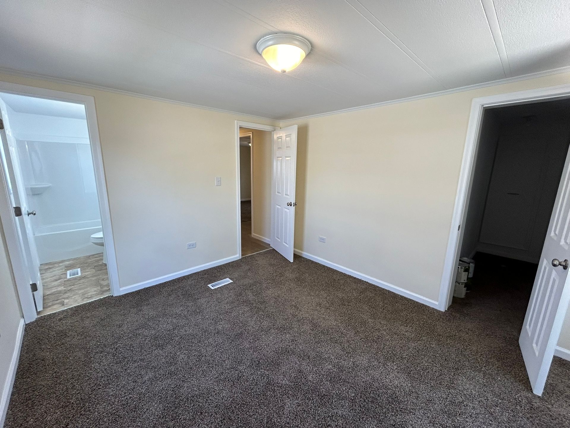 An empty bedroom with a brown carpet and white walls.