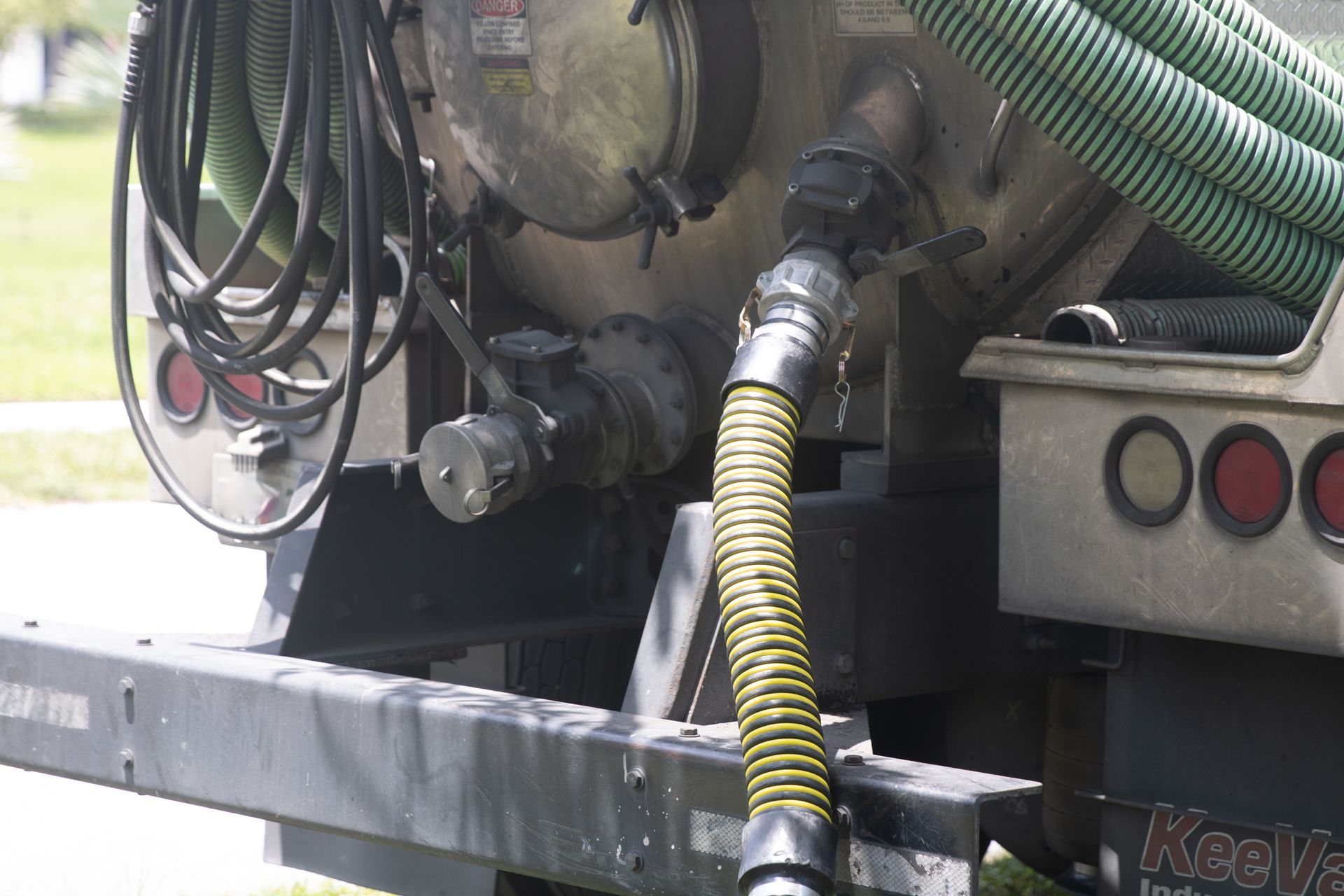 Industrial vacuum truck hoses connected to a tank, with coiled green and yellow hoses Industrial vacuum truck hoses connected to a tank, with coiled green and yellow hoses