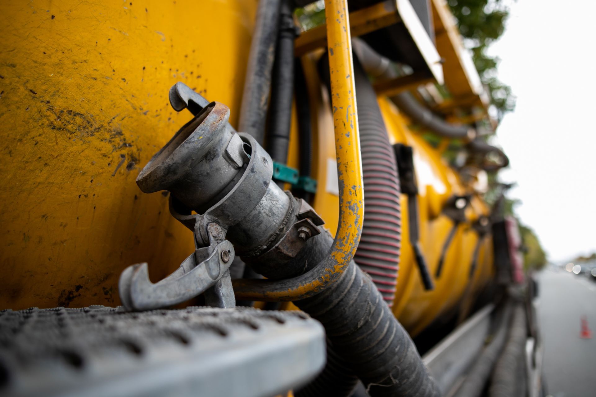 Yellow utility truck with close-up industrial hose and metal pipe on roadside Yellow utility truck with close-up industrial hose and metal pipe on roadside