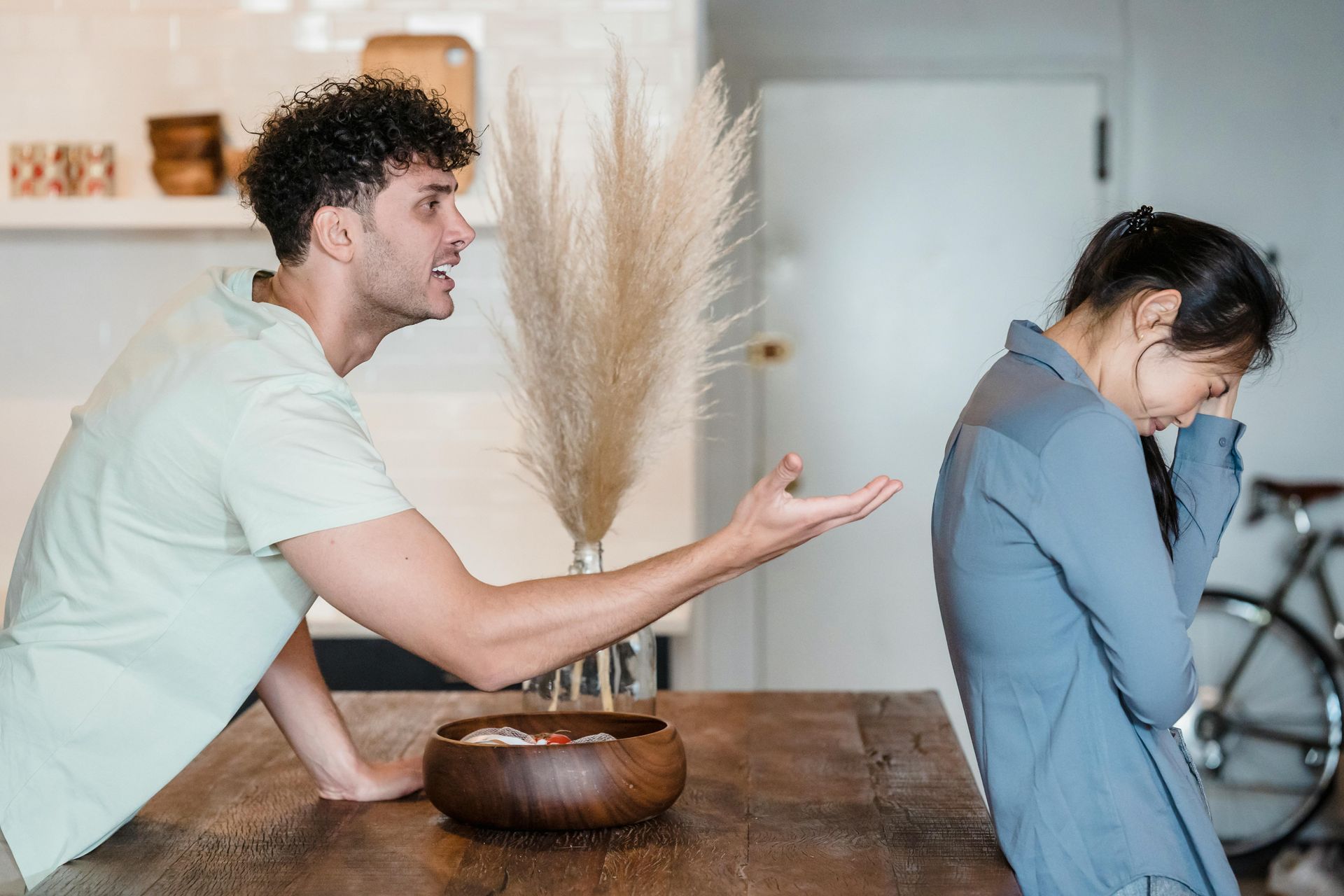 Man yelling, gesturing towards a woman crying in a kitchen.