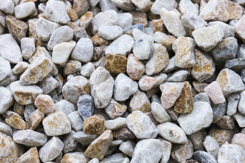Pile of mixed light-colored pebbles, varying from beige to gray.