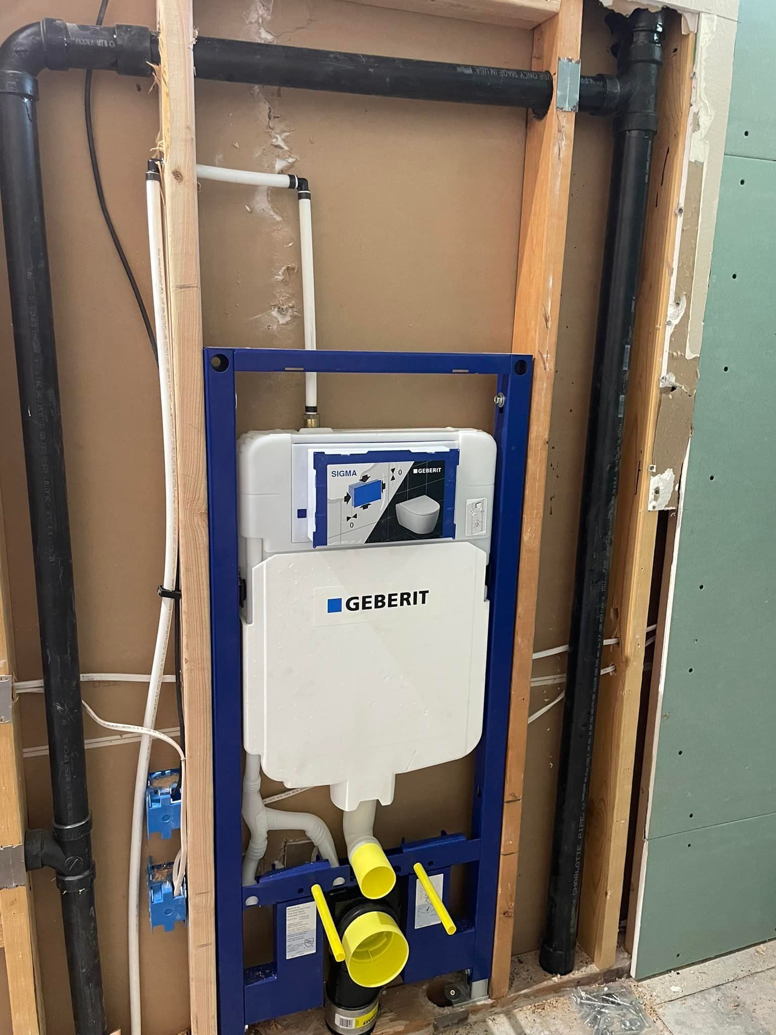 Blue toilet tank frame and plumbing pipes within a wall's wooden frame.
