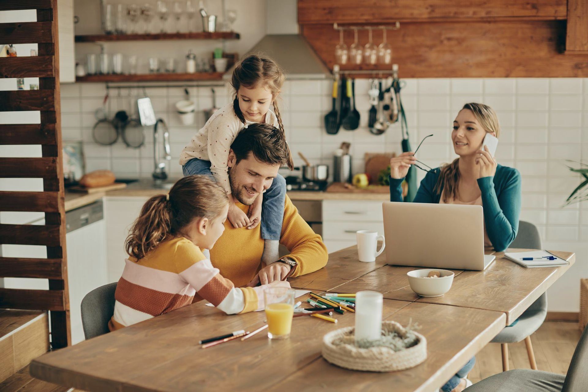 A family is sitting at a table with a laptop. 