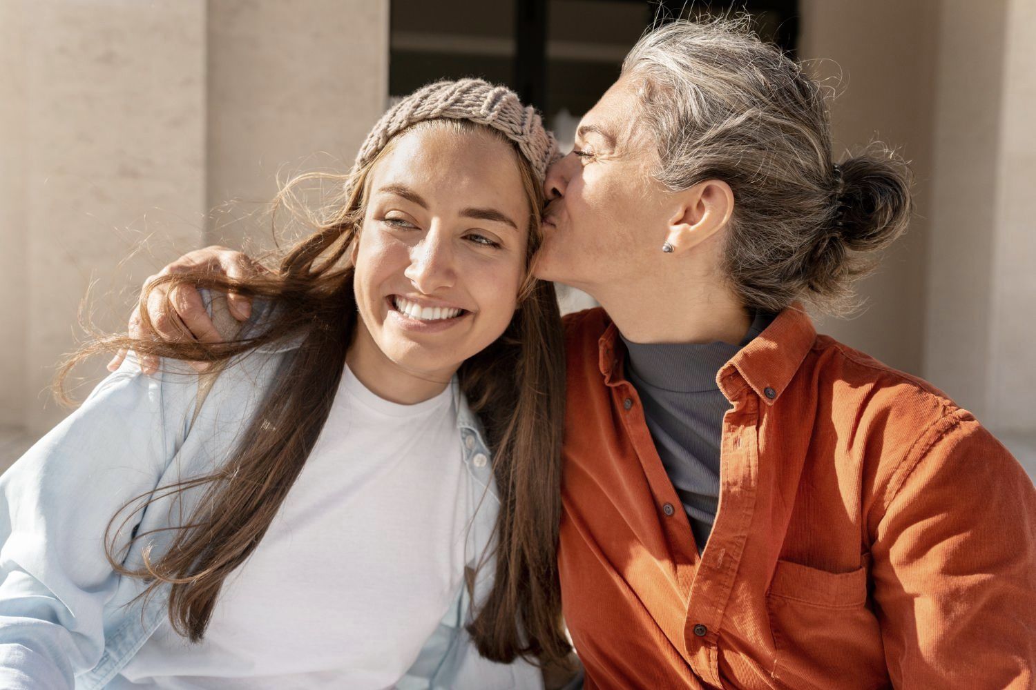 A woman is kissing a younger woman on the cheek.