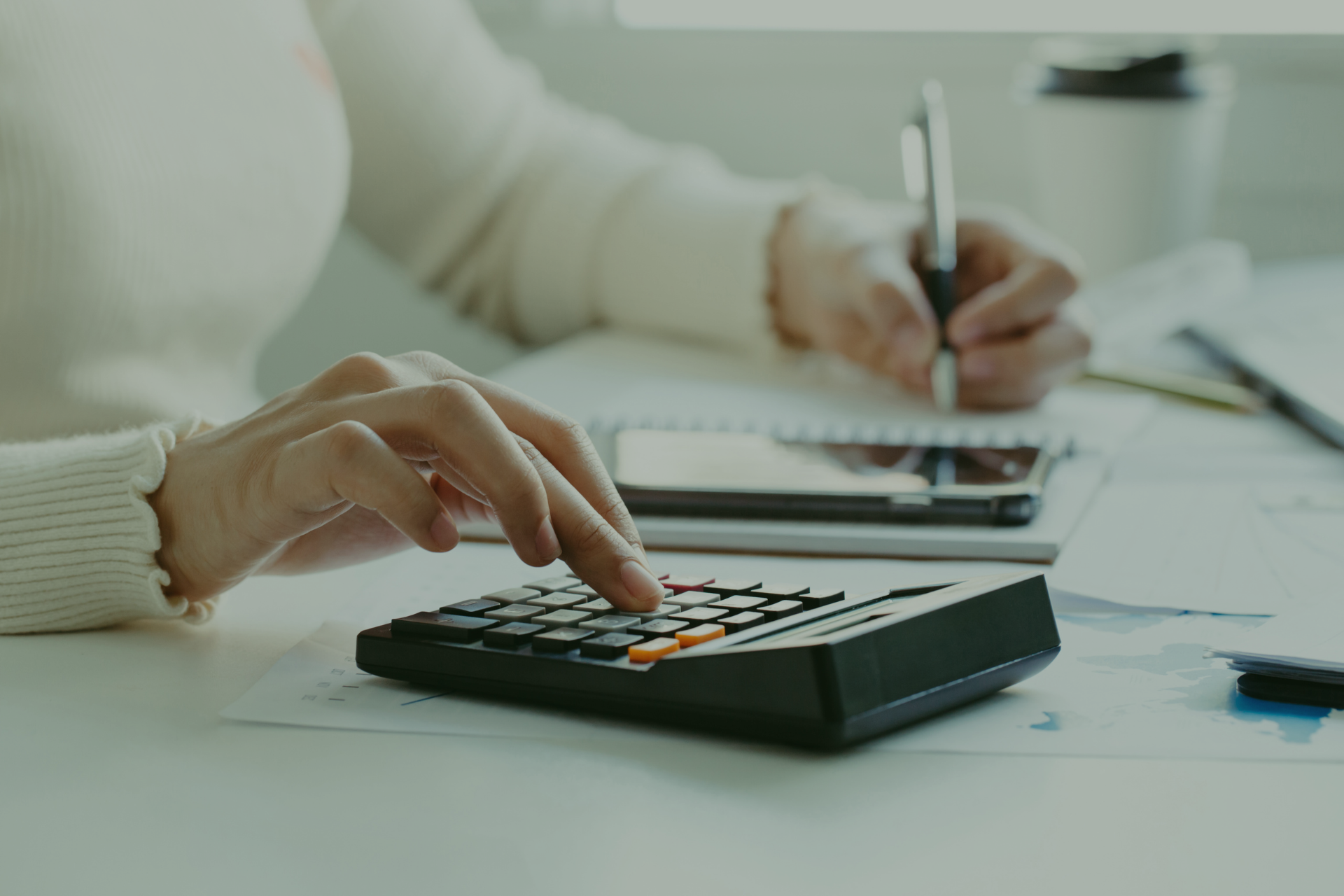 A person is using a calculator and writing on a piece of paper.