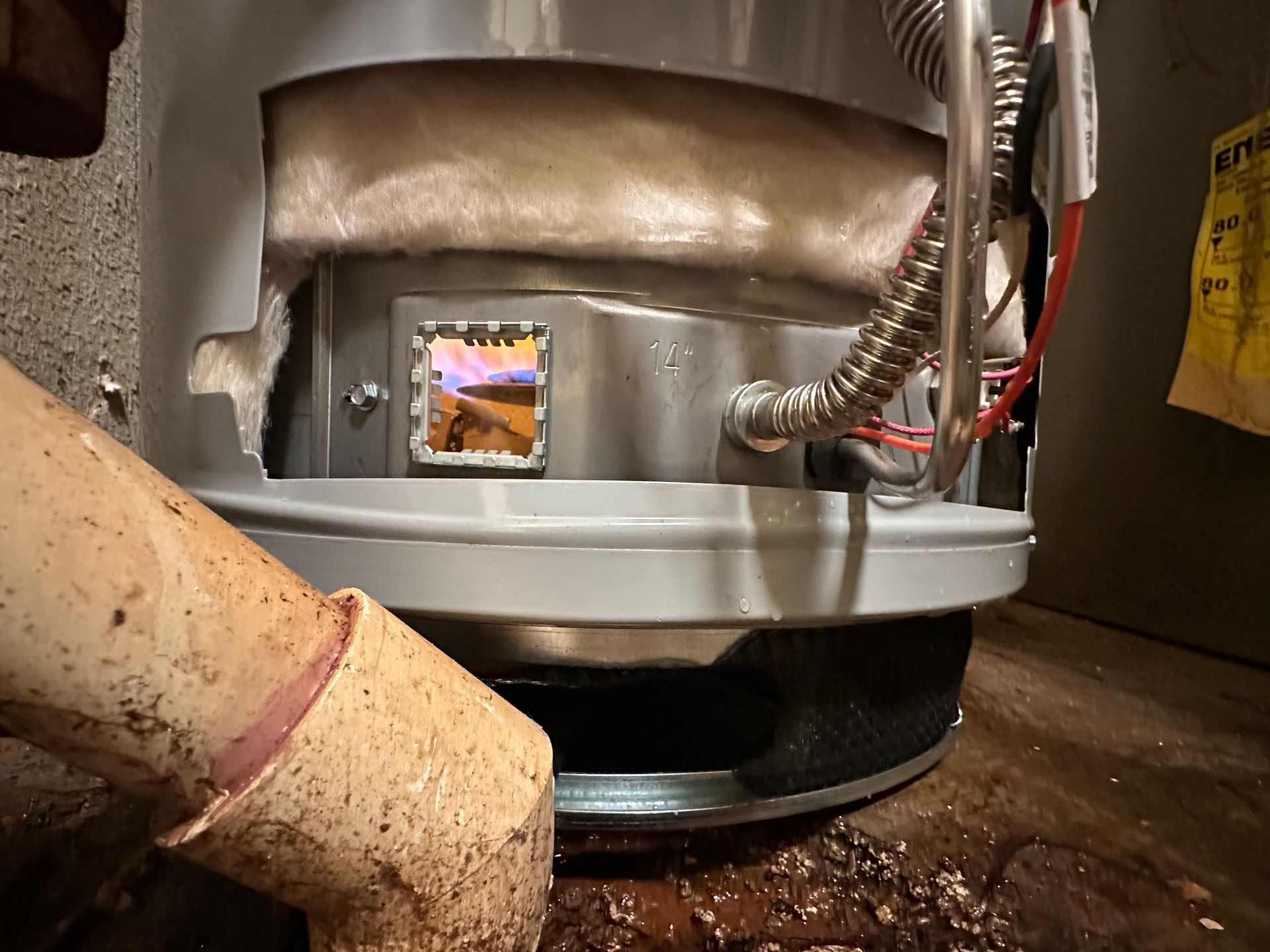 Plumber using a wrench to install fittings on top of a white water heater