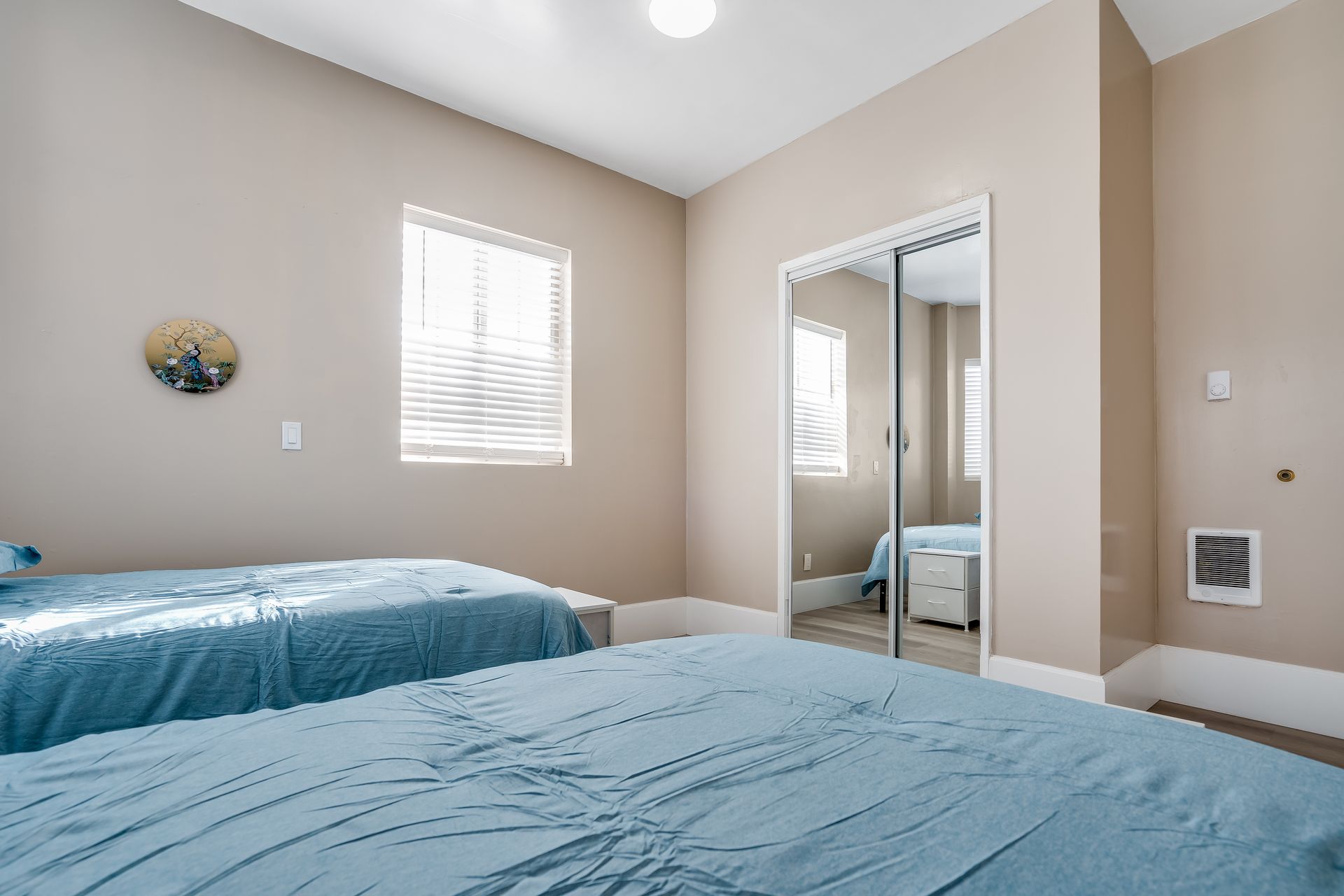 A bedroom with two beds and a sliding glass door.