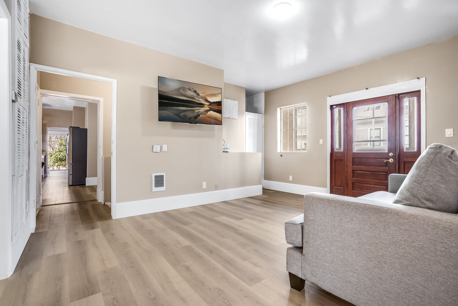 A living room with a couch and a flat screen tv on the wall.