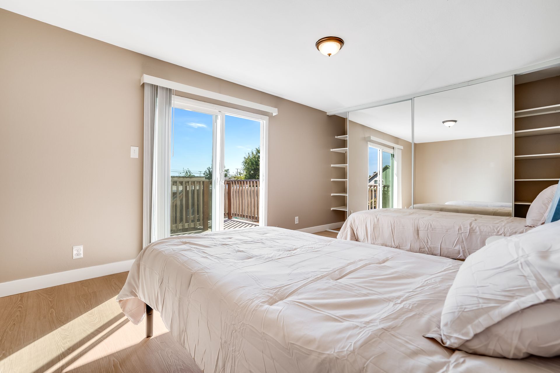 A bedroom with two beds and a sliding glass door.
