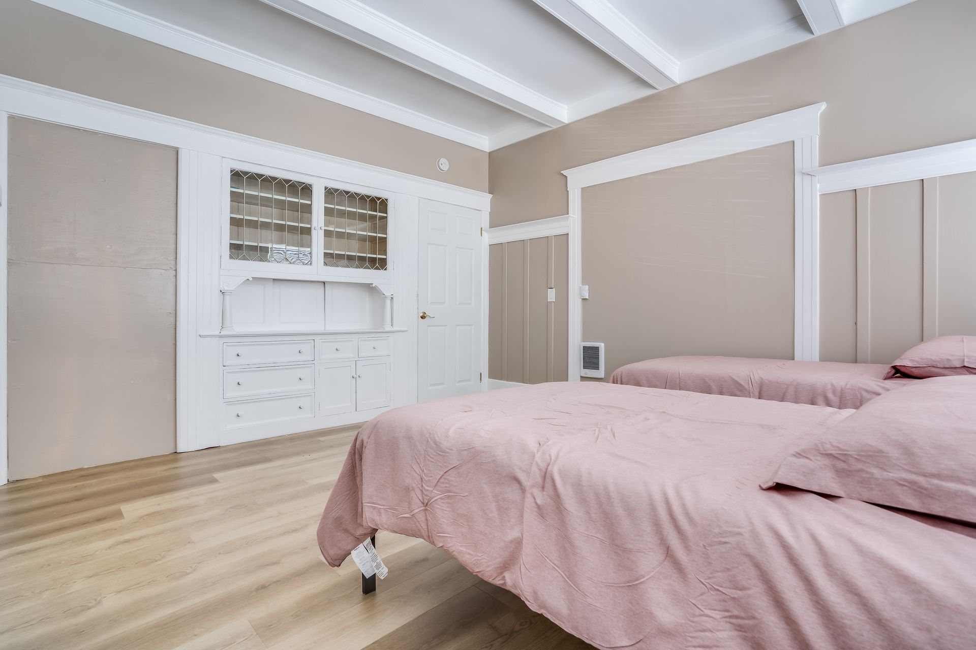 A bedroom with two beds and a wooden floor.