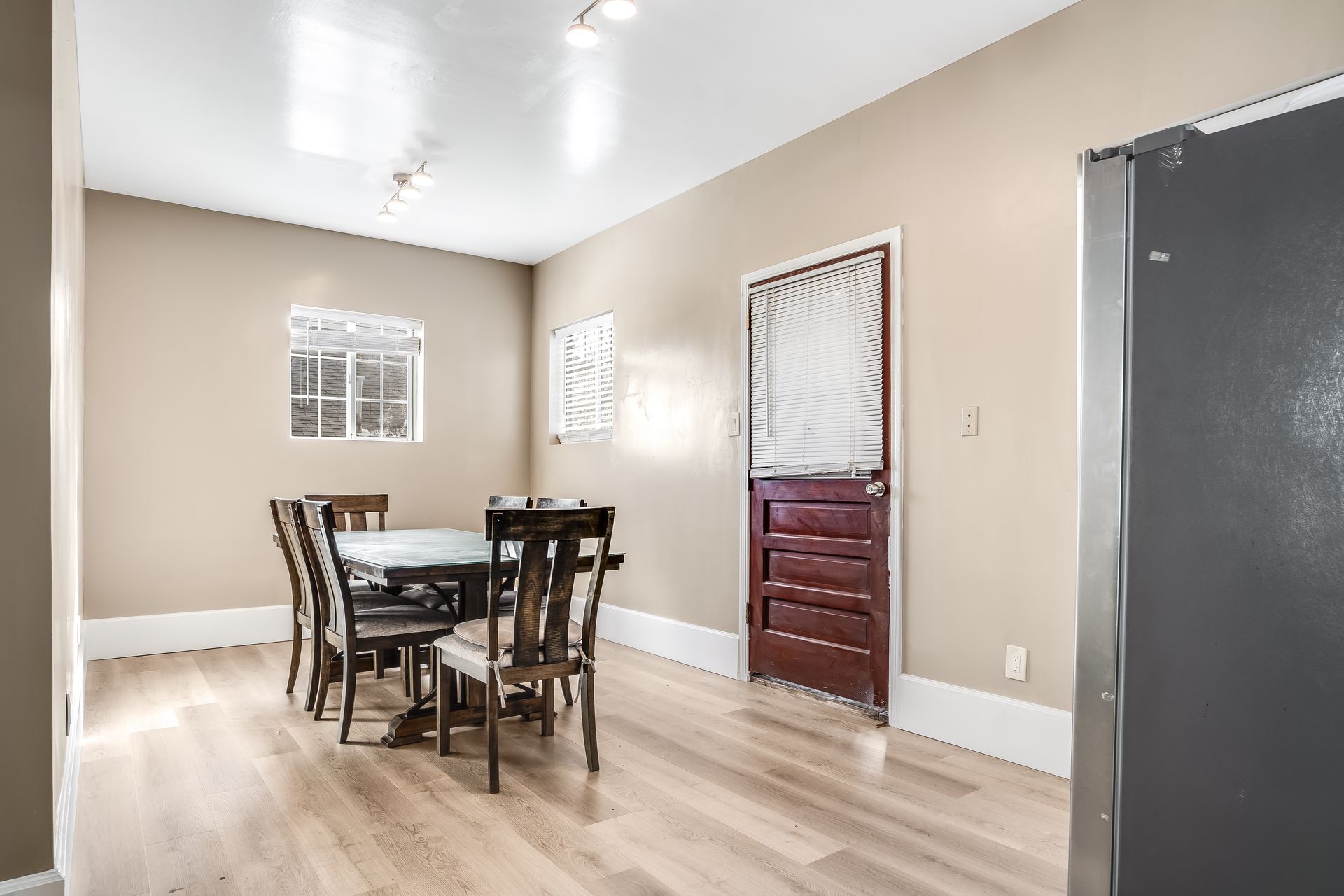 A dining room with a table and chairs and a red door.