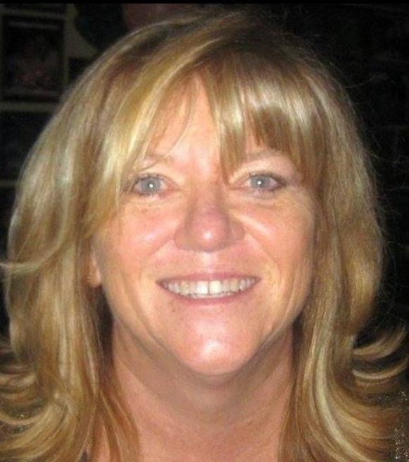 Smiling woman with blonde hair against a dark background