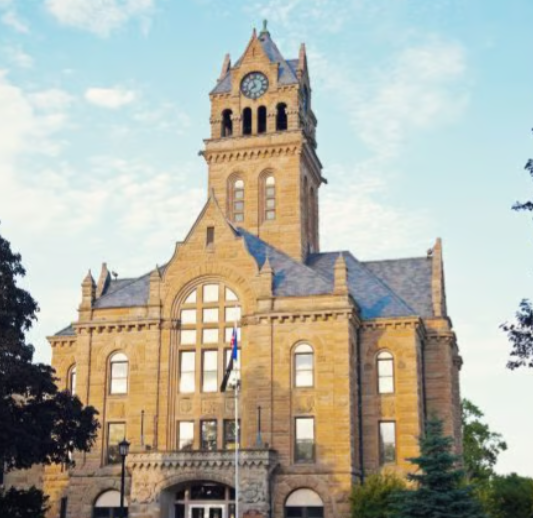 Historic tan stone clock tower building under a blue sky