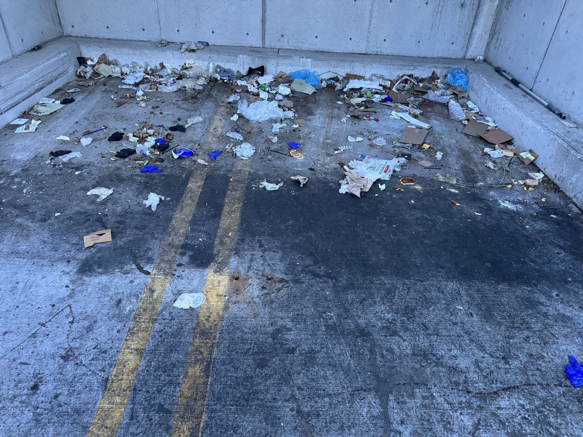 A photo of a dirty dumpster pad before it was deep cleaned by JET's special pressure washing equipment