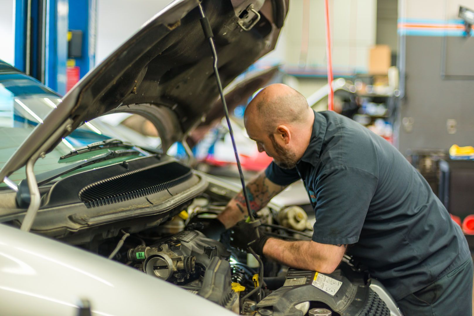 A man is working on the engine of a car in a garage. | The Garage in Renton