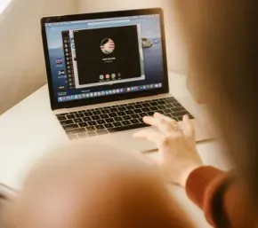 Person using a laptop on a bright staircase, with a blurred child in the foreground