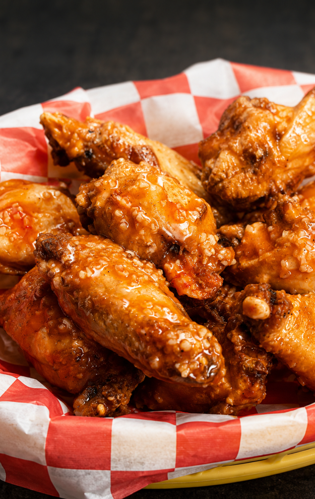 Basket of glazed chicken wings in red-and-white checkered paper