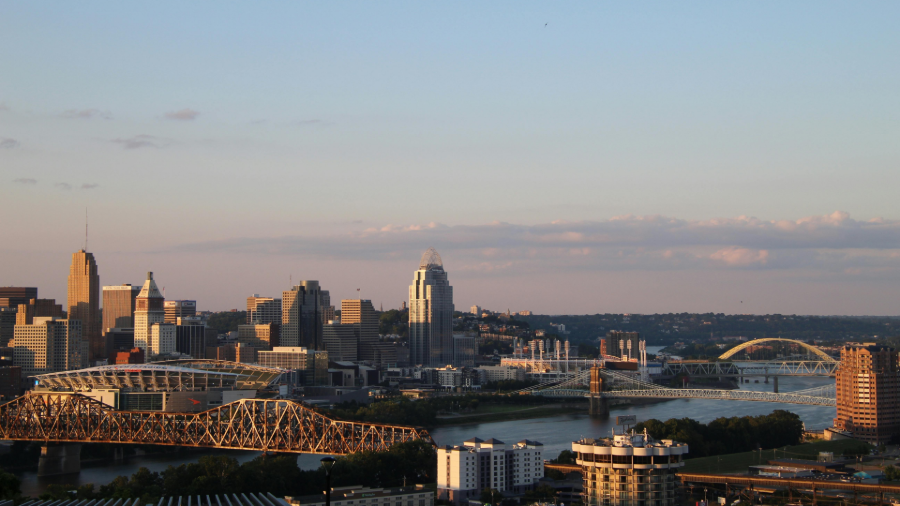 City skyline at sunset with bridges spanning a river under a clear sky.