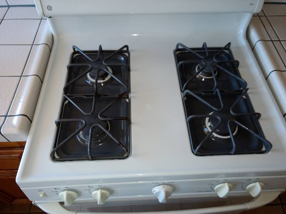 White gas stovetop with four black burner grates and control knobs.