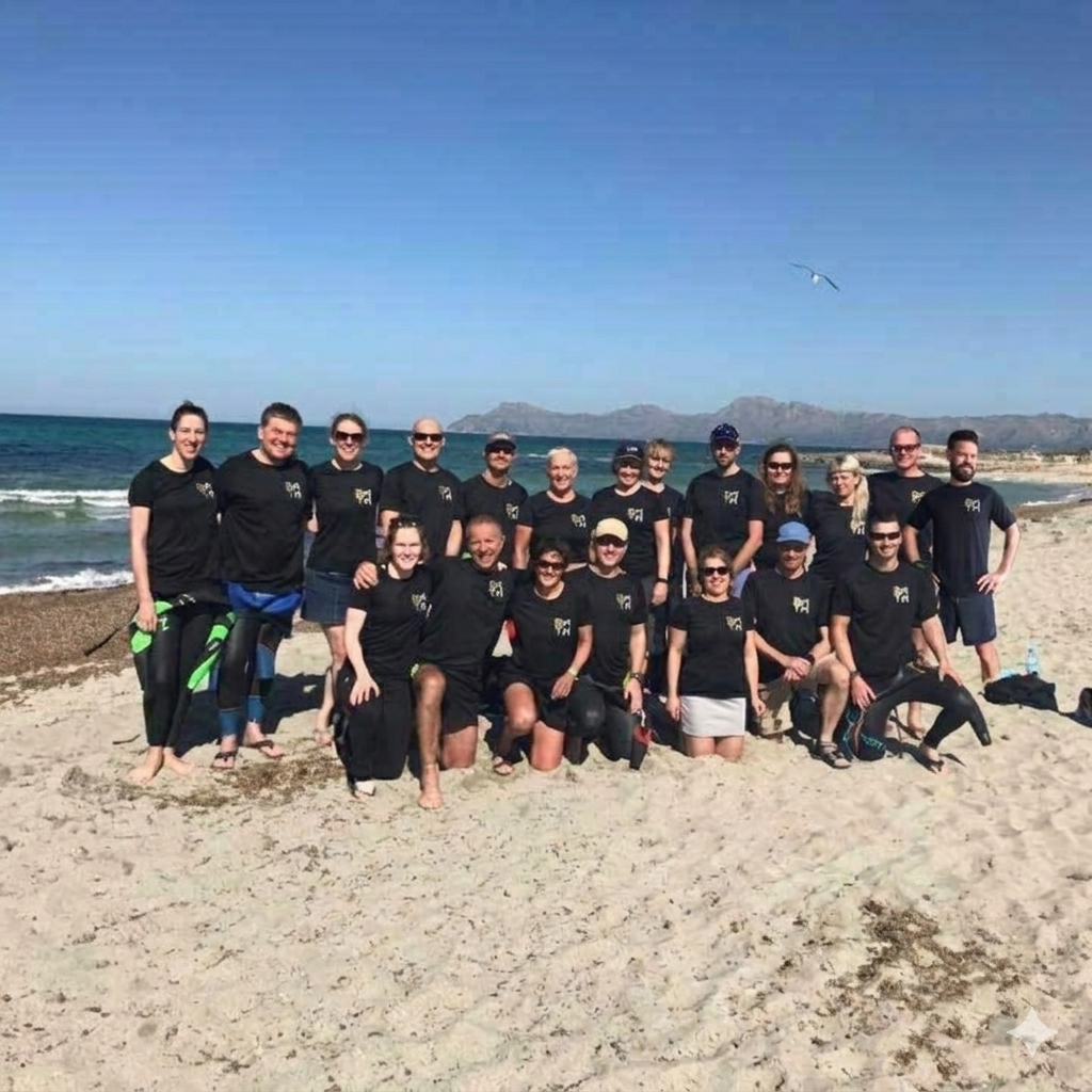 Group of people in black shirts posing on a sunny beach with ocean waves behind them
